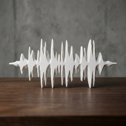 Sculpture 3D imprimée en forme d'onde sonore, de couleur blanche, posée sur une table en bois devant un mur gris béton.